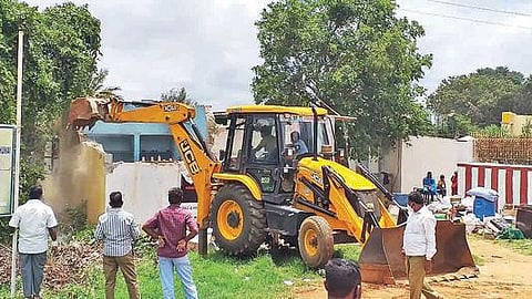 அரசு நிலத்தை ஆக்கிரமித்து கட்டிய வீட்டை இடித்து அகற்றும் பணியில் ஈடுபட்ட நெடுஞ்சாலைத்துறை மற்றும் வருவாய் துறையினர்.       படம்: ஜோதி ரவிசுகுமார்.