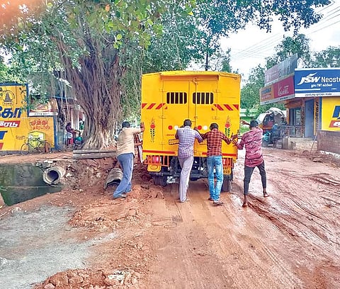 குமரி மாவட்டம் சேனாப்பள்ளி சந்திப்பில் பாசன கால்வாய் சீரமைப்பு பணி நடந்த பின்னர் நெடுஞ்சாலையை முறையாக சமன்படுத்தாததால் அப்பகுதி புதைகுழியாக  மாறி  விட்டது. பள்ளத்தில் சிக்கிய வாகனத்தை மீட்பதற்காக போராடும் இளைஞர்கள்.    							            படம்: எல்.மோகன்.