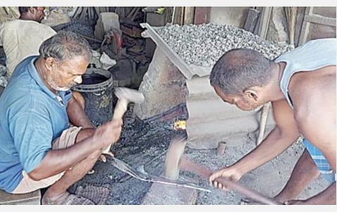 திருப்புவனத்தில் உள்ள இரும்புப் பட்டறையில் அரிவாள் தயாரிக்கும் பணியில் ஈடுபட்டுள்ள தொழிலாளர்கள். 
