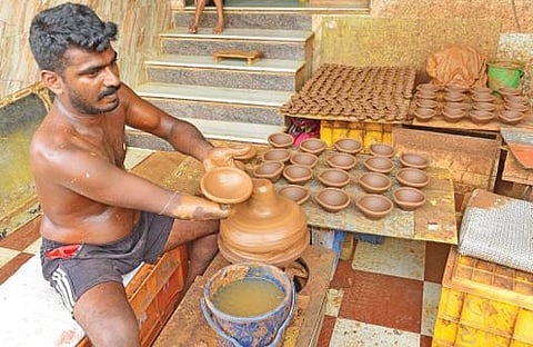 கார்த்திகை தீபத் திருநாளை முன்னிட்டு அகல் விளக்குகளை தயாரிக்கும் மதுரை பரவையைச் சேர்ந்த மண்பாண்டக் கலைஞர் மாற்றுத் திறனாளி ஆர்.வேல்முருகன். படம்: எஸ்.கிருஷ்ணமூர்த்தி