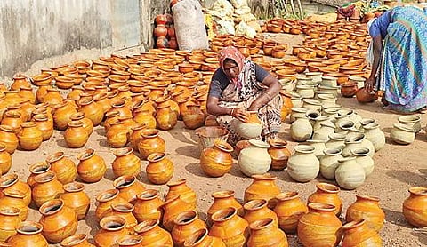 பூவந்தியில் பொங்கல் பண்டிகைக்கு தயாராகும் மண் பானையில் வர்ணம் பூசும் பெண் தொழிலாளி.