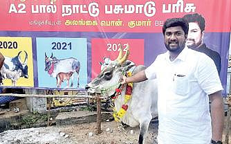 சிறந்த இரண்டாவது காளைக்கு வழங்கப்பட்ட நாட்டின பசு மாட்டுடன் பொன்குமார்.