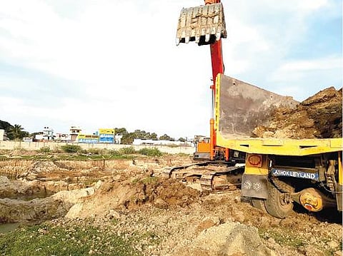 ஆற்றின் நடுவே ஜேசிபி மூலம் மண் அள்ளப்படுகிறது.