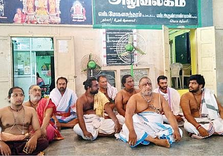 குமாரவயலூர் சுப்பிரமணியசுவாமி கோயிலில் நேற்று பூஜை செய்து பக்தர்களுக்கு பிரசாதம் வழங்கிய  புதிய அர்ச்சகர். (அடுத்த படம்) இதற்கு எதிர்ப்பு தெரிவித்து கோயில் வளாகத்தில் போராட்டத்தில் ஈடுபட்ட பரம்பரை அர்ச்சகர்கள்.