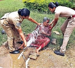தற்கொலை மிரட்டல் விடுத்த  மூதாட்டியின் உடலில் தண்ணீரை ஊற்றிய பெண் காவலர்கள். படம்: இரா.தினேஷ்குமார்.