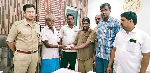 பணப்பையை தவறவிட்டவரிடம் பையை ஒப்படைக்கும் அரசுப் பேருந்து நடத்துநர் வேல்முருகன்.