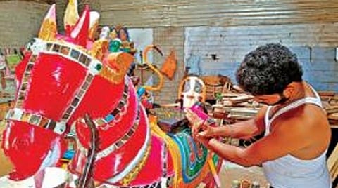 நாமக்கல் அருகே கூலிப்பட்டியில் மரத்தால் வடிவமைக்கப்பட்ட சிலைக்கு வர்ணம் தீட்டும் இளைஞர் அங்குராஜ்