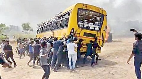 பள்ளி வளாகத்தில் நிறுத்தி வைக்கப்பட்டிருந்த பேருந்தை சாய்க்கும் போராட்டக்காரர்கள்.
