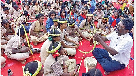 மதுரை தமுக்கம் மைதானத்தில் நடைபெறும் புத்தகத் திருவிழாவில் மாணவ, மாணவிகளுக்கு தென்னைமர ஓலைகளை பயன்படுத்தி கலைப் பொருட்களை உருவாக்கும் முறை குறித்து கற்றுத் தரும் ஆசிரியர் திலகராஜ். படம்: எஸ்.கிருஷ்ணமூர்த்தி