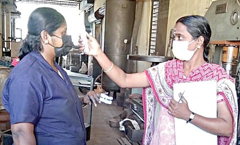கோவை தொழில் நிறுவனம்  ஒன்றில் தொழிலாளரின் உடல்வெப்பத்தை பரிசோதிக்கும் ஊழியர்.