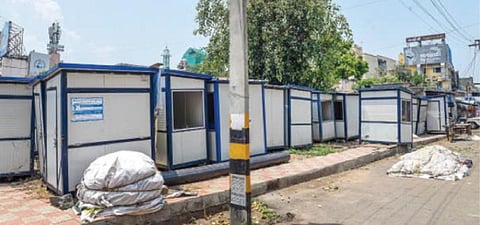சேலம் திருமணிமுத்தாற்றை மேம்படுத்தும் திட்டத்தில் ஆற்றின் நடைபாதை பகுதிகளில் வைப்பதற்காக வாங்கப்பட்ட பெட்டிக்கடைகள் வணிக வளாகம் அருகே சாலையோரம் பயனற்று கிடக்கின்றன. படம்: எஸ். குரு பிரசாத்