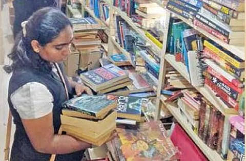 தனக்கு தேவையான புத்தகங்களை நூலகத்திலிருந்து தேடி எடுத்த வாசகி.
