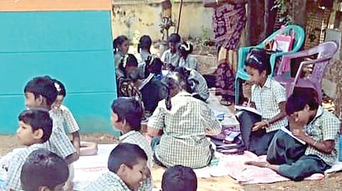 சிங்கம்புணரி சீரணி அரங்கம் அருகே ஊராட்சி ஒன்றிய மாதிரி தொடக்கப் பள்ளியில் இடநெருக்கடியால் மரத்தடியில் பயிலும் குழந்தைகள்.