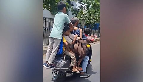 ஸ்கூட்டரில் குழந்தைகளுடன் பயணம் செய்யும் நபர்