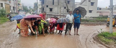 தருமபுரி ஆட்சியர் அலுவலகம் அருகே ராமன் நகர் பகுதியில் சகதியாக மாறிய சாலையில் நாற்று நடும் போராட்டத்தில் ஈடுபட்ட குடியிருப்புவாசிகள்.