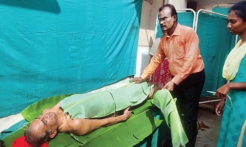 பவானி அரசு மருத்துவமனையில் வாழை இலை குளியல் சிகிச்சை அளிக்கும் சித்த மருத்துவர் எஸ்.கண்ணுசாமி.