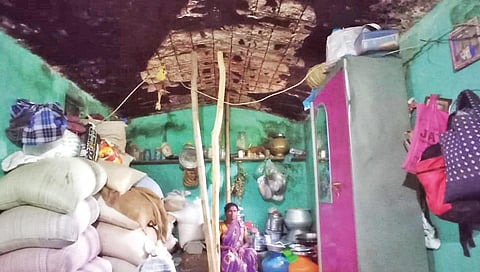 கொடகரை மலைக் கிராமத்தில் உள்ள தொகுப்பு வீட்டின் மேற்கூரை சிமென்ட் பூச்சு உதிர்ந்த நிலையில், மரக்கம்பு மூலம் மேற்கூரைக்கு முட்டுக் கொடுக்கப்பட்டுள்ள வீட்டில் வசிக்கும் பெண்.
