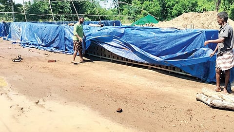 ஈரசெங்கல்லை தார்படுதாவைக் கொண்டு மூடும் பணியில் தொழிலாளர்கள். | இடம்: உடையாளூர்.