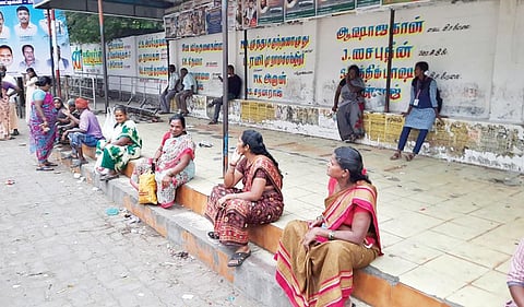 திருவண்ணாமலை பெரியார் சிலைபேருந்து நிறுத்தத்தில் இருக்கைகள் இல்லாததால் தரையில் அமர்ந்துள்ள பயணிகள். | படம்: இரா.தினேஷ்குமார்.