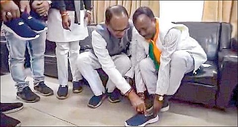 பாஜக தலைவர் ராம்தாஸ் புரிக்கு காலணி அணிவித்த முன்னாள் முதல்வர் சிவராஜ் சிங் சவுகான். படம்: பிடிஐ