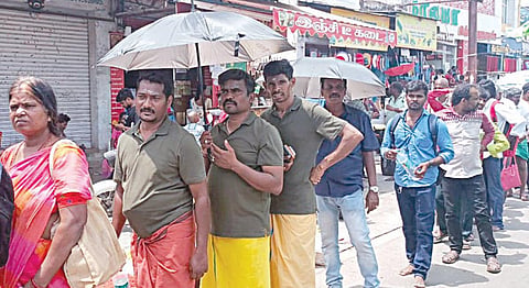 திருவண்ணாமலை அண்ணாமலையார் கோயிலில் வெயிலின் தாக்கத்தால் குடைபிடித்துவாறு கோயிலுக்கு வெளியே நீண்ட வரிசையில் காத்திருந்த பக்தர்கள்.