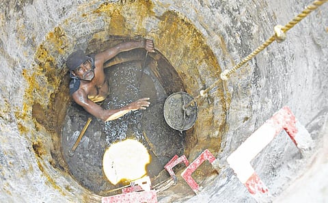 சேலம் குகை மூங்கப்பாடி தெருவில் ஆபத்தான முறையில் பாதாள சாக்கடை தொட்டியில் இறங்கி அடைப்பை சரிசெய்ய கழிவுகளை அகற்றும் தொழிலாளி. 
| படம்: எஸ். குரு பிரசாத் |