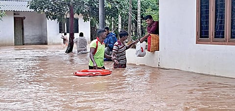 கூடலூர் அருகே இருவயல்  பகுதியில் மழை நீர் புகுந்த வீட்டுக்குள் சிக்கிய நபர்களை மீட்கும் தீயணைப்புத் துறையினர்.