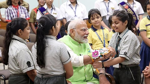 சகோதரத்துவத்தை போற்றும் ரக் ஷா பந்தன் தினத்தையொட்டி டெல்லியில் நேற்று பிரதமர் நரேந்திர மோடிக்கு ராக்கி கயிறை கட்டி விடும் பள்ளி மாணவிகள். படம்: பிடிஐ
