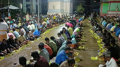 வத்தலகுண்டு அருகே தருமத்துப்பட்டியில் நடந்த கோயில் திருவிழாவில், கொட்டும் மழையையும் பொருட்படுத்தாது திறந்தவெளியில் அமர்ந்து கறிவிருந்தில் பங்கேற்ற ஆண்கள்.