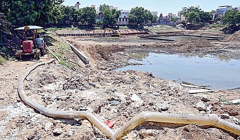 ஆக்கிரமிப்பை அகற்றாமல் குளத்தில் நடைபெறும் சீரமைப்பு பணிகள். | படம்: எம். முத்துகணேஷ் |