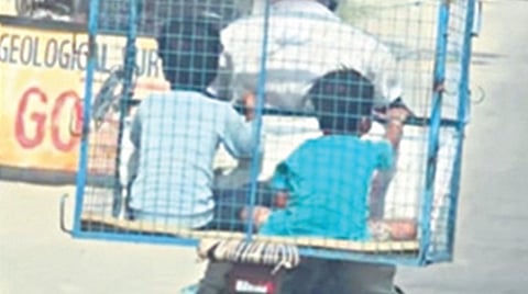 கோழிக்கூண்டில் அமர்ந்து தந்தை பைக்கில் பயணித்த மகன்கள்