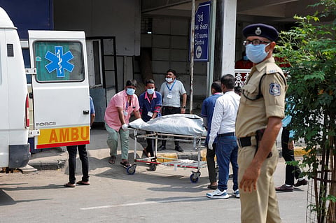 விமான விபத்தில் உயிரிழந்தவரின் உடலை குளிரூட்டப்பட்ட அறைக்கு கொண்டு செல்லும் மருத்துவப் பணியாளர்கள்