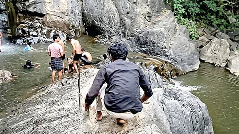 தாண்டிக்குடி அருகேயுள்ள புல்லாவெளி அருவி பகுதிக்கு ஆபத்தான முறையில் செல்லும் இளைஞர்கள். 