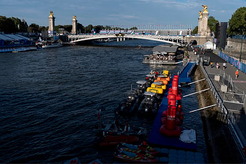 Watercraft and buoys sit along the Seine river as the triathlon event venue on the Pont Alexandre III bridge stands in the background at the 2024 Summer Olympics on  Sunday (July 28) in Paris.