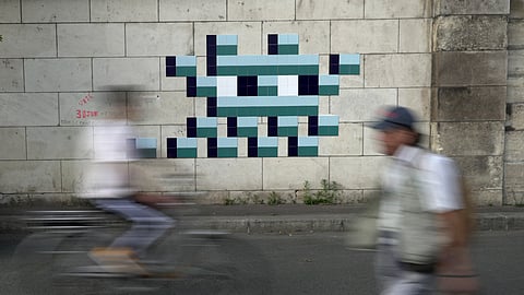 A  cyclist rides in front of an Olympic-themed new mosaic by the mysterious French street artist known only by the name Invader
