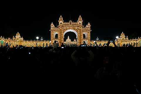 Visitors watch illuminated Amba Palace, a major tourist attraction, as part of the celebrations on the eve of final day of the Dussehra festivities, in Mysuru, on Friday, Oct. 11, 2024