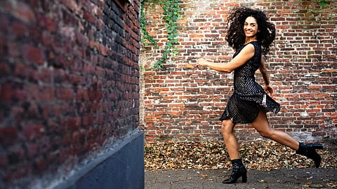 Dancer, actress and now stand-up comedienne Rukmini Vijayakumar poses mid-step in front of a wall