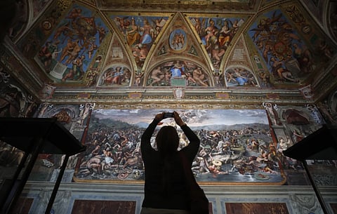 A visitor admires a Raphael Room inside the Vatican Museums 