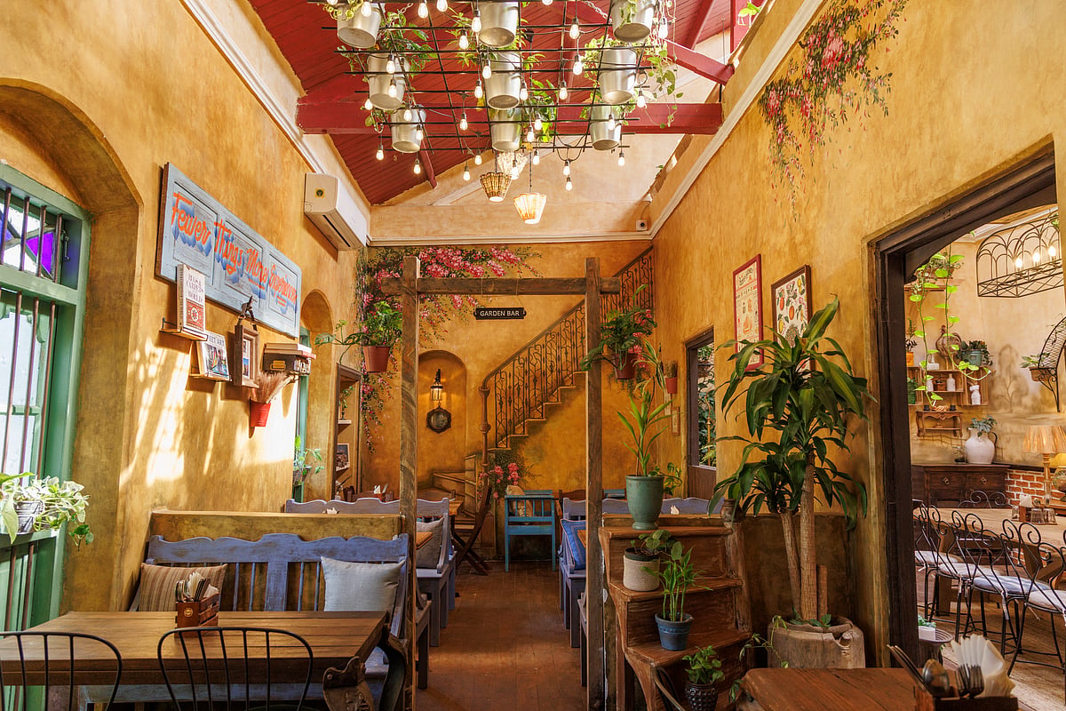 Ochre walls, green windows, painted floral details and dining tables inside Everhome Café in Bandra.
