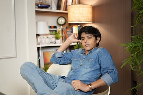 Actor Yudhvir Ahlawat posing for a portrait while leaning back in a modern white chair, dressed in a casual denim-on-denim outfit