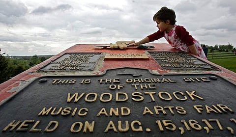 Emma Cenholt, 3, of Trumbull, Conn, playing on a memorial at the site of the Woodstock Music and Arts Fair in Bethel, NY. Woodstock 50 is less than a few months away. (AP Photo/Mike Groll)