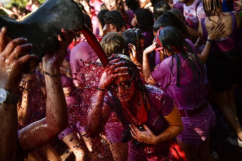 A reveler is covered in wine as people take part in this summer battle, throwing thousands of litres of red wine over each other, in the village of Haro, northern Spain. (AP Photo/Alvaro Barrientos)
