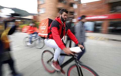 Venezuelan courier Samuel Romero, 21, takes an order to a Rappi customer on his bicycle in Bogota, Colombia. (AP Photo/Fernando Vergara)