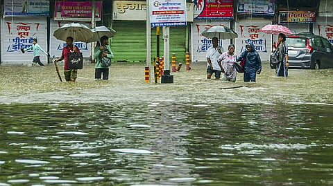 Mumbai: Pedestrians wade through an inundated road amid rains, in Mumbai, Monday, May 26, 2025.