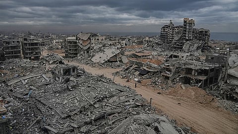Displaced Palestinians walk amid destroyed buildings in the Shati refugee camp in Gaza City, 