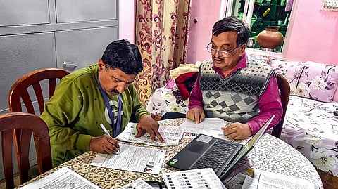 A Booth Level Officer (BLO) assists a voter in filling out the enumeration form for the special intensive revision (SIR) of electoral rolls