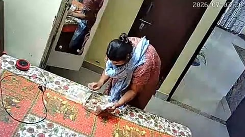 CCTV camera in the house captures the woman checking the contents of a box