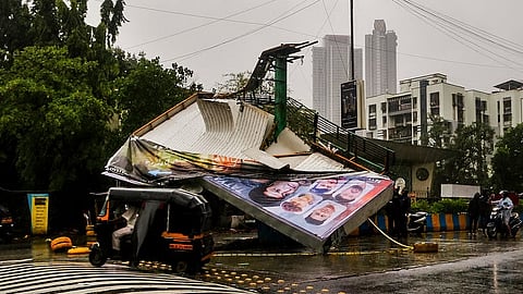 A hoarding lies damaged after strong winds uproot it from a road divider on Pokhran Road amid heavy rainfall, in Thane, Maharashtra, Monday, July 6, 2026