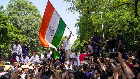 Leader of Opposition in the Lok Sabha Rahul Gandhi waves the national flag while standing atop police barricades after being stopped by security personnel.