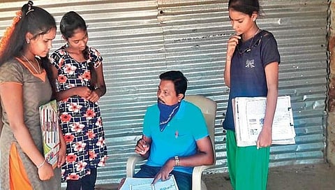 ಬಾಗಿಲು ಹಾಕಿರುವ ಅಂಗಡಿಯೊಂದರ ಮುಂದೆ ಮಕ್ಕಳಿಗೆ ಪಾಠ ಮಾಡುತ್ತಿರುವ ಶಿಕ್ಷಕ ಸ್ವಾಮಿ ಎಸ್ ಎಂ